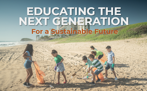 Children pick up litter on a sandy beach, holding trash bags and wearing gloves. Text above reads: Educating the Next Generation for a Sustainable Future. Green grass and buildings are visible in the background.